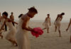 la foto a colori mostra alcune danzatrici di colore vestite di bianco; una di loro ha sulle mani un pezzo di stoffa rosso