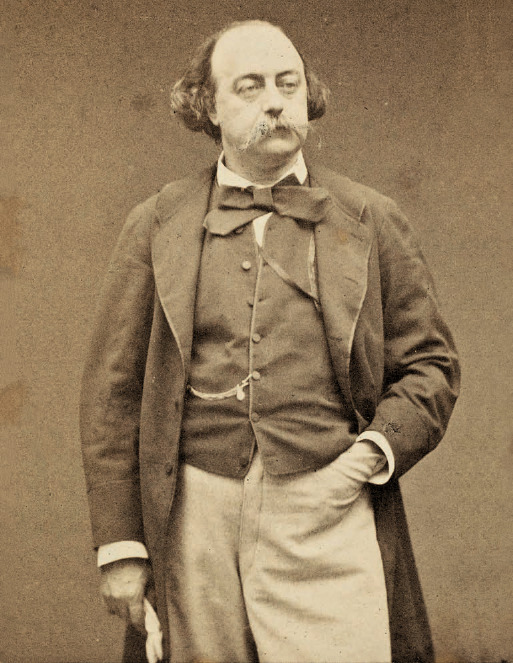 il dipinto in bianco e nero mostra un ritratto dello scrittore Gustave Flaubert, che indossa giacca e gilet scuri, pantaloni chiari, papillon e un guanto sulla mano destra