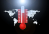 foto a colori di un mappamondo con, al centro, un termometro che segna le elevate temperature atmosferiche di colore rosso