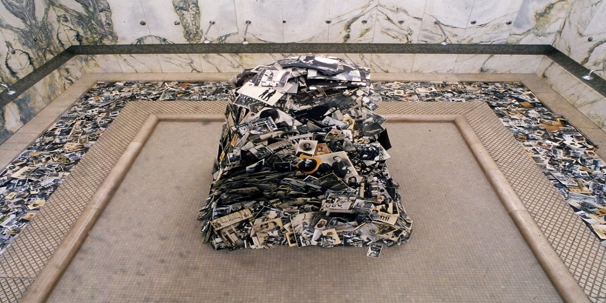 la foto a colori mostra una scultura di Fabio Mauri che rappresenta un mucchio di riviste poggiate per terra che formano un monte