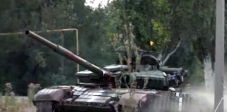 L'immagine mostra un carro armato durante l'assalto della Russia nella regione ucraina del Donbass. Il mezzo bellico avanza su un terreno polveroso con alcuni alberi nello sfondo