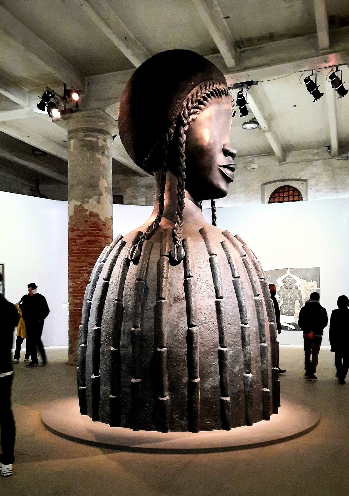 La foto mostra una delle opere di Simone Leigh, esposte alla Biennale di Venezia 22. Un gigantesco mezzobusto di una donna in stile africaneggiante al centro della Corderia dell'Arsenale